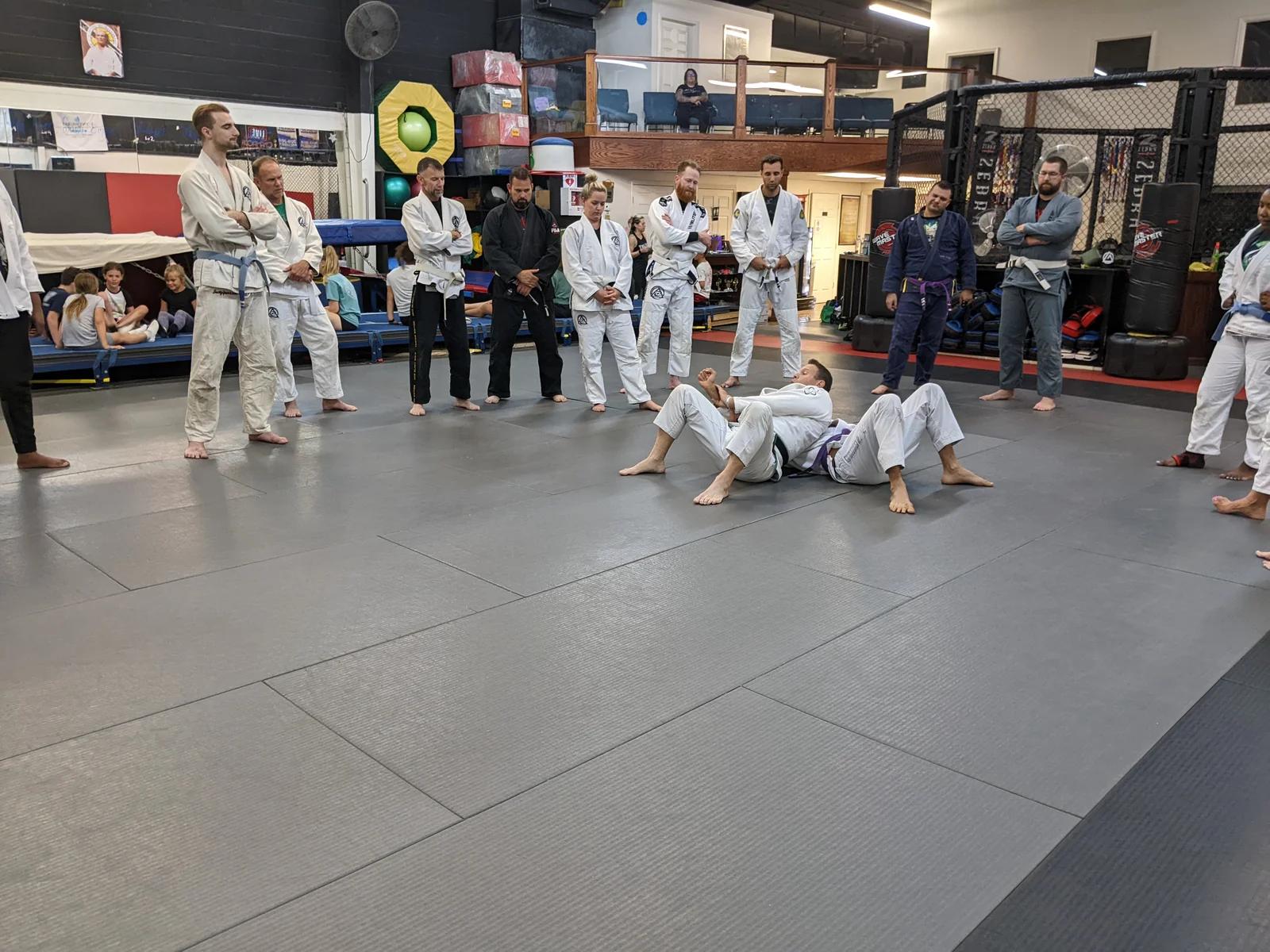 Students watching a Jiu-Jitsu technique demonstration on the mats at The Edge